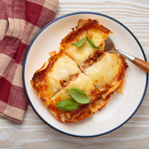 A plate of lasagna, a checkered napkin, and a fork