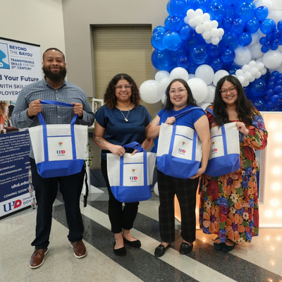 four university of houston-downtown staff members hold tote bags with the mental health matters conference logo