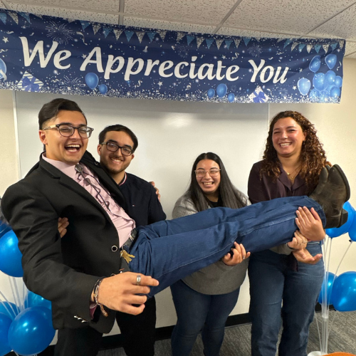 Four student employees in human resources laugh and smile at the university of houston downtown