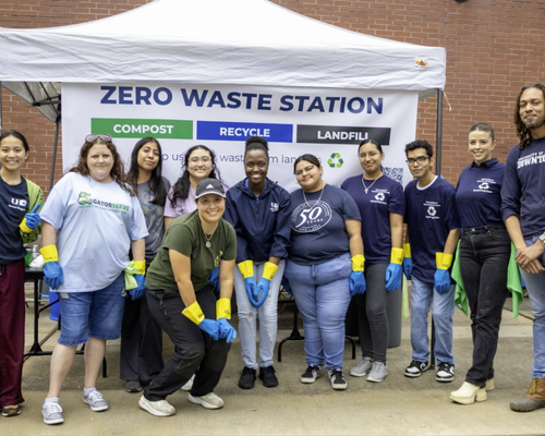 Students and staff pose in gloves and university of houston-downtown branded shirts at a zero waste station at the university's chili cook-off