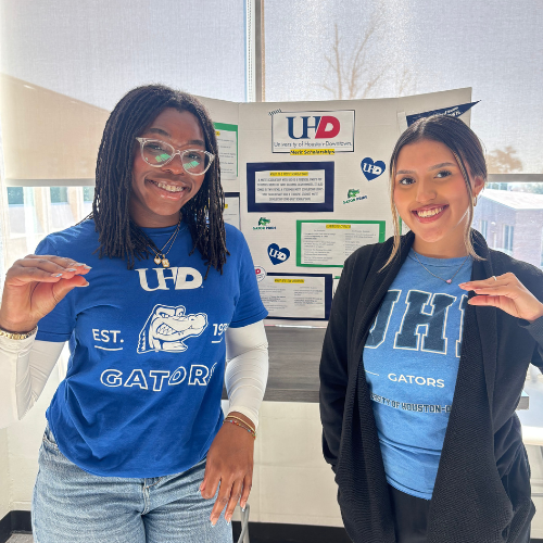 Two university of houston-downtown merit scholars and students hold up gator handsigns while tabling at san jacinto college south for Bayou Bound.