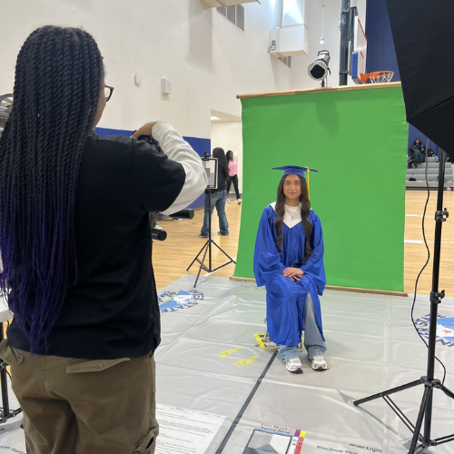 A University of Houston-Downtown Upward Bound participant and graduating high school senior from KIPP Journey Collegiate School wears graduation regalia at a photoshoot. 