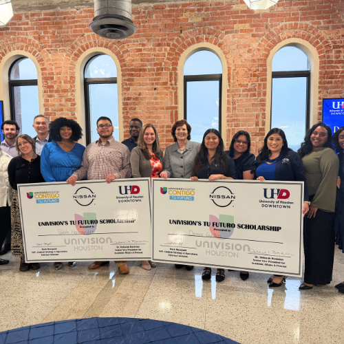 Tu Futuro scholarship recipients hold oversized checks with univision, nissan, and the university of houston-downtown logo. The University of Houston-Downtown's Enrollment Management team, Deborah Bordelon, and Univision staff smile.