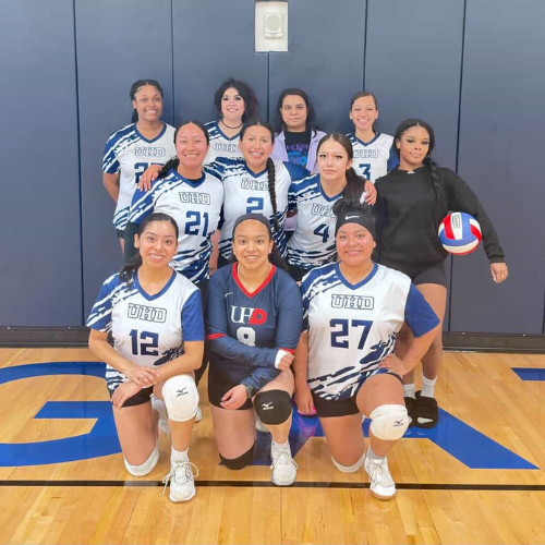 The University of Houston-Downtown's womens volleyball team smiles on a volleyball court at the wellness and success center at the university of houston downtown.