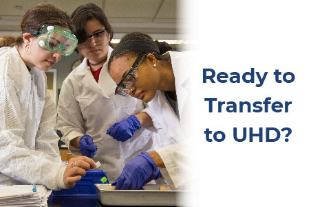 Students wearing lab coats and goggles, reviewing their lab work in a laboratory setting.